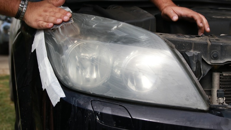 A person taping surrounding area before performing headlight restoration
