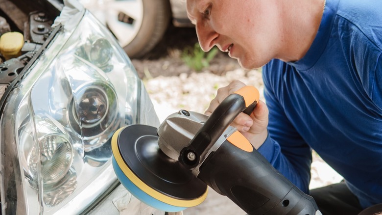 A person polishing headlight with orbital buffer as part of a restoration