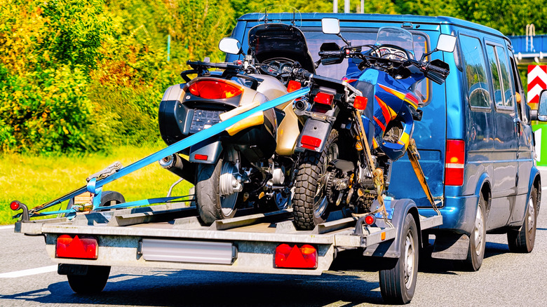 Two motorcycles strapped on a trailer.