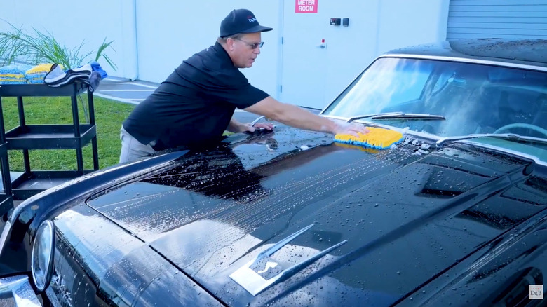 A person cleaning the hood of a black car