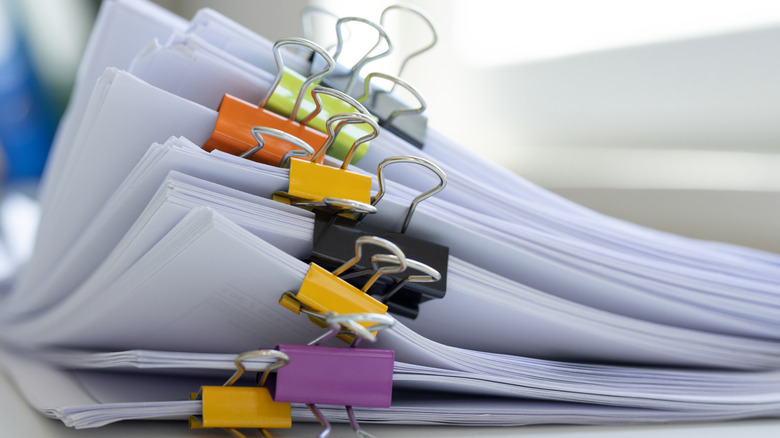 A stack of papers with many colorful clips.