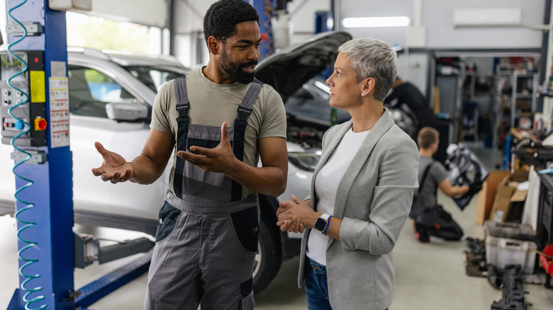 A mechanic and a customer speak in a garage.