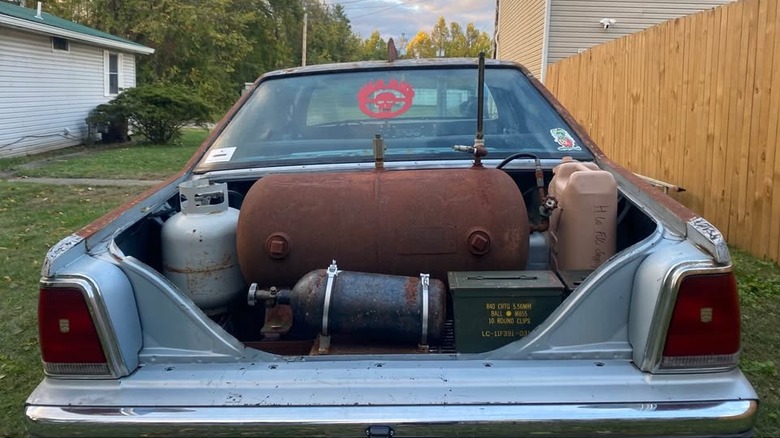 Rear of the car, showing the open trunk full of tanks