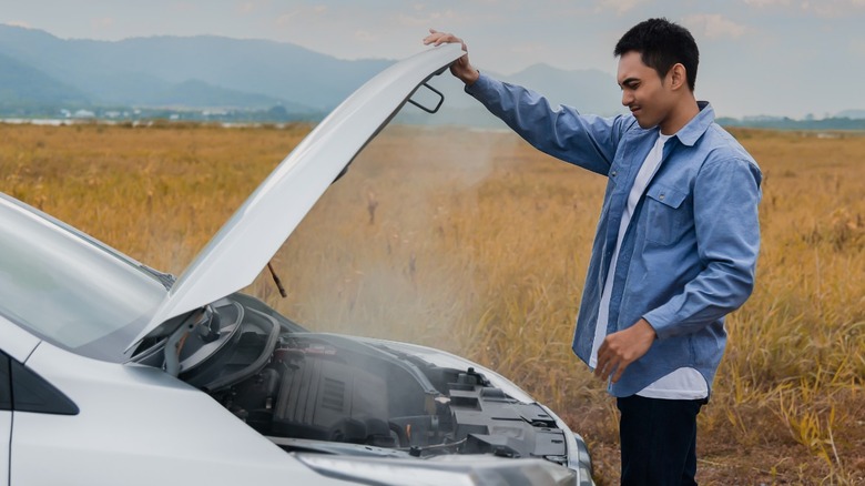 Man opening hood of overheated car