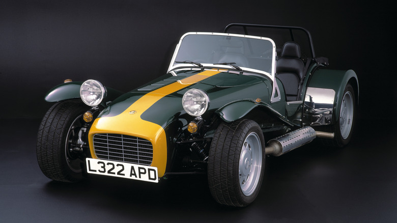 A studio shot of a green and yellow Caterham Seven sports car.