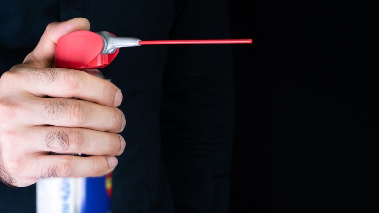 A manus holding a tin of spray lubricant