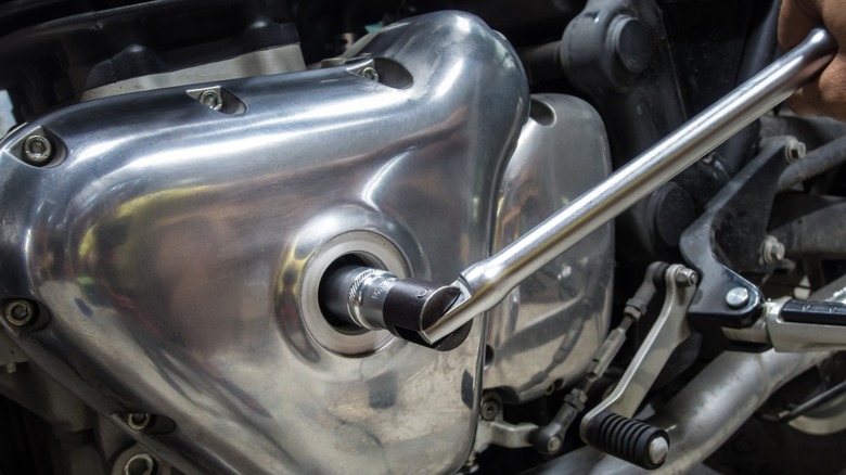 A motorcycle mechanic uses a breaker barroom to loosen a bolt