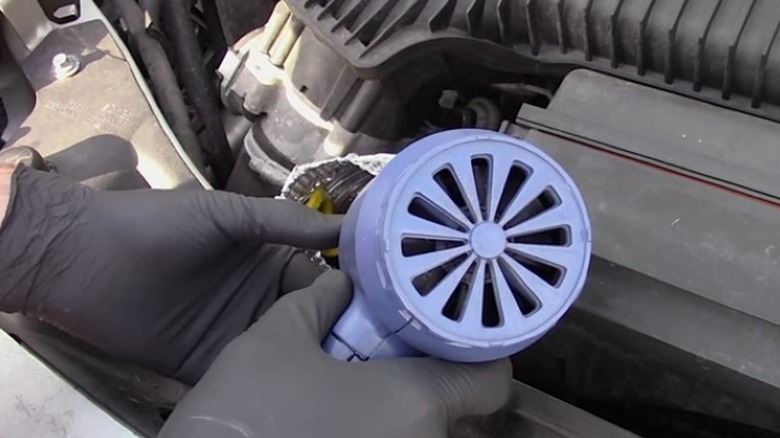 Using a heat gun to apply heat to a stuck oil dipstick.