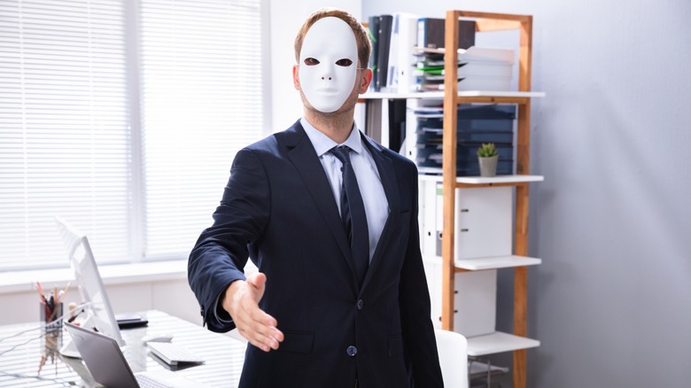 Masked man extends his hand for a handshake
