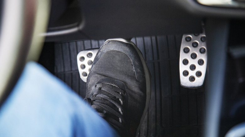 A person in black sneakers stepping on the brake pedal