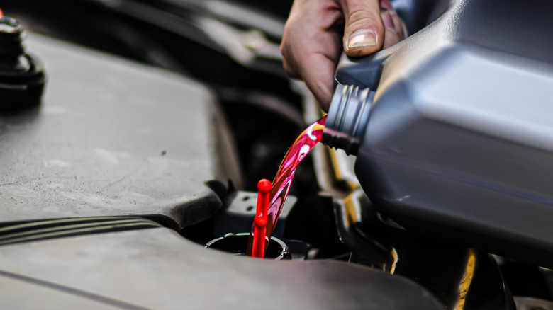 A car owner pouring fresh coolant into the reservoir