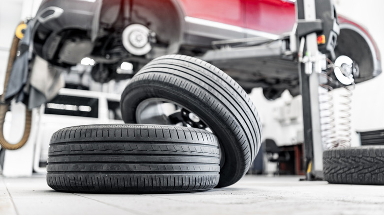 Two wheels and tires with a lifted car in the background