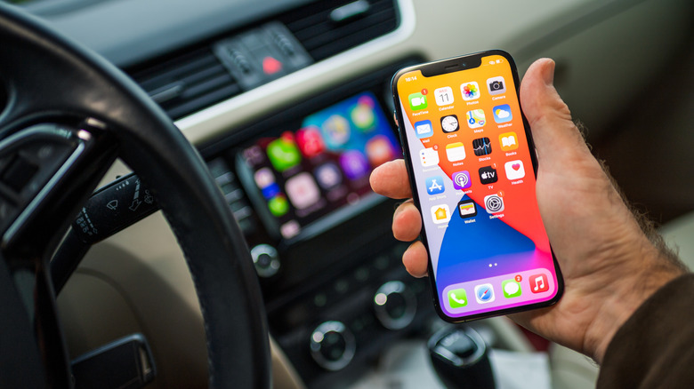 A person holding an iPhone inside a car with Apple Car Play