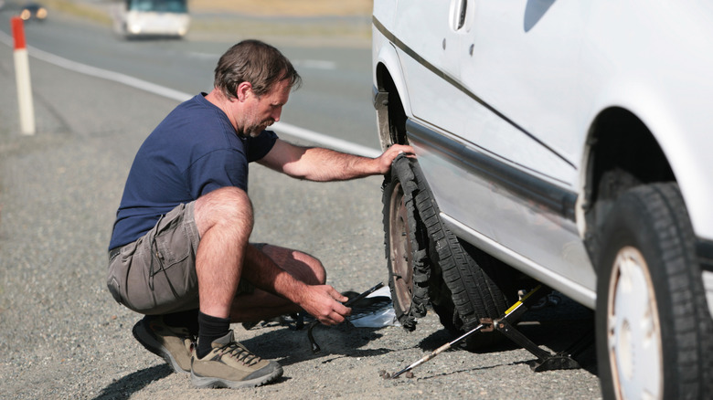 A man removing a blown tyre connected nan thoroughfare side