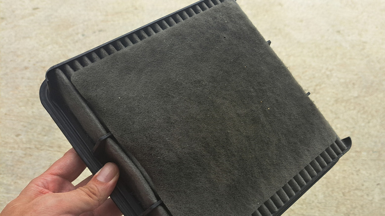 Mechanic holding an old and filthy cabin air filter