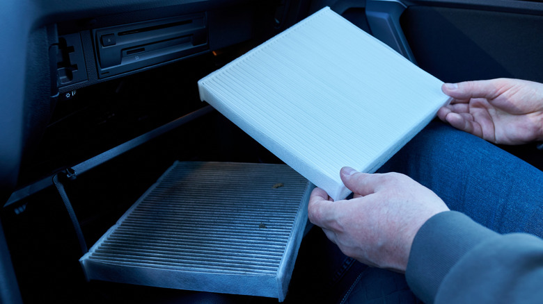 A car owner replacing the old cabin filter with a new one
