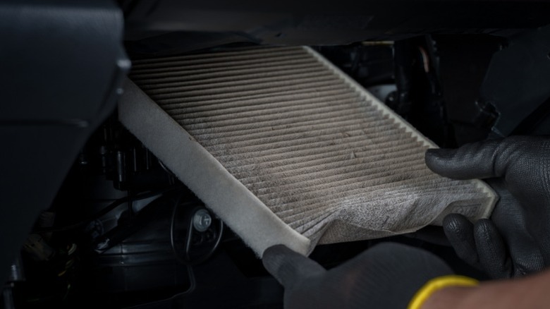 A mechanic replacing a dirty cabin air filter