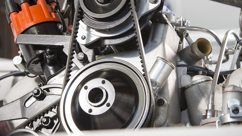 The harmonic balancer on an freshly rebuild BMW engine being lowered into the engine bay of a BMW 507.