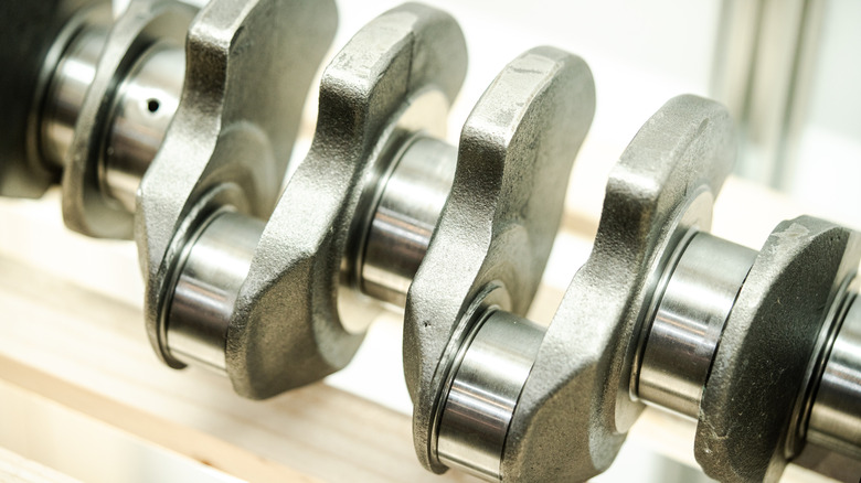 A fresh and clean engine crankshaft from an automobile, looking all shiny and pristine.