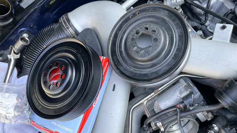 A fresh new harmonic balancer on the left, a worn out harmonic balancer on the left, on top of a twin-turbo 2.7-liter V6.