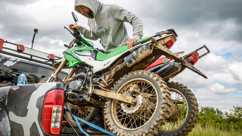 A man strapping down dirt bikes to a truck bed