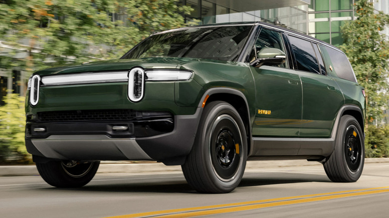 Rivian R1S driving down city street with buildings on one side