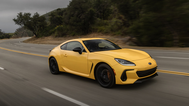 A yellow Subaru BRZ with black rims on a roadway.
