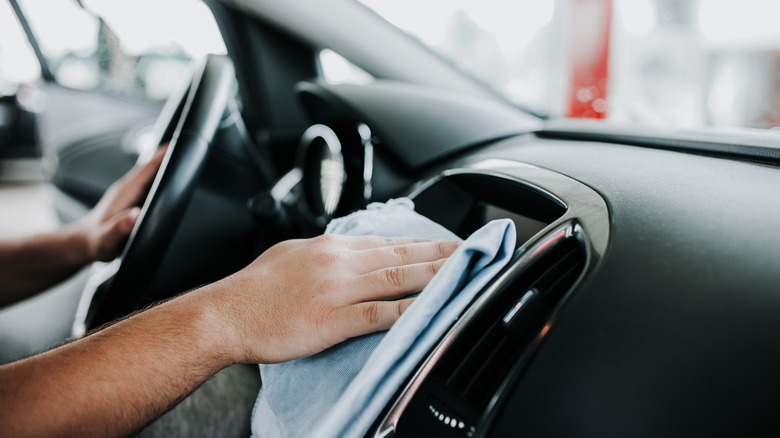 A person wipes their instrument cluster with a microfiber towel.
