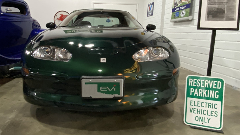 A green GM EV1 in a museum next to a 