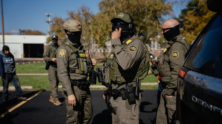 U.S. federal agents stand near unmarked cars as they make multiple detainments in a far north side neighborhood of the city on October 31, 2025, in Chicago, Illinois.
