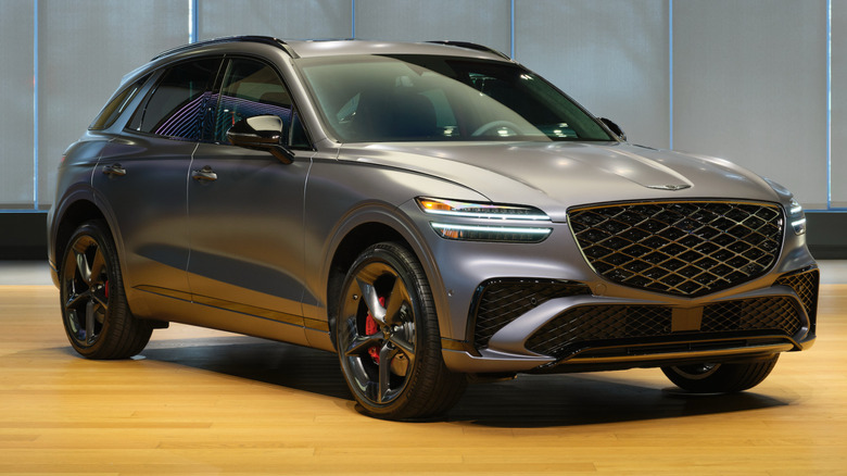 Front three-quarters shot of a gray Genesis GV70 parked in a room on a wood floor