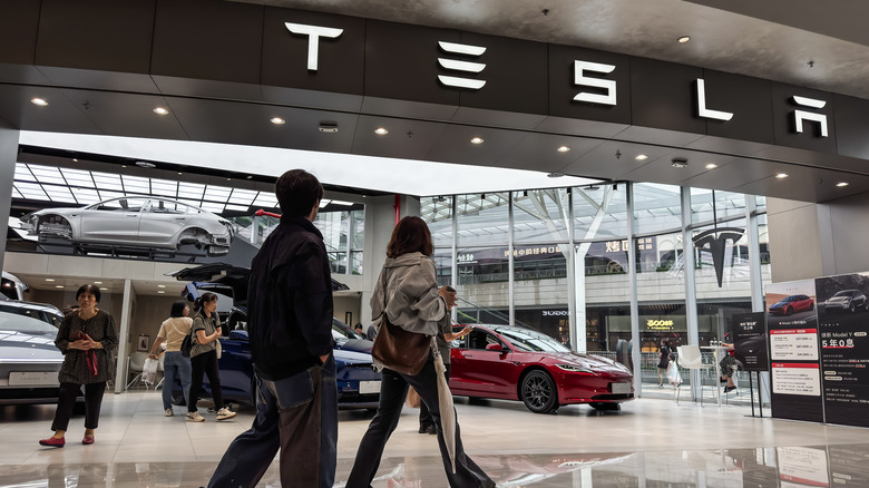CHONGQING, CHINA - MAY 31: Shoppers walk past a Tesla showroom displaying various electric vehicle models on May 31, 2025, in Chongqing, China. As trade tensions between China and the United States persist, Tesla continues to navigate the world's largest EV market, balancing localization strategies with its identity as a leading American innovator. (Photo by Cheng Xin/Getty Images)