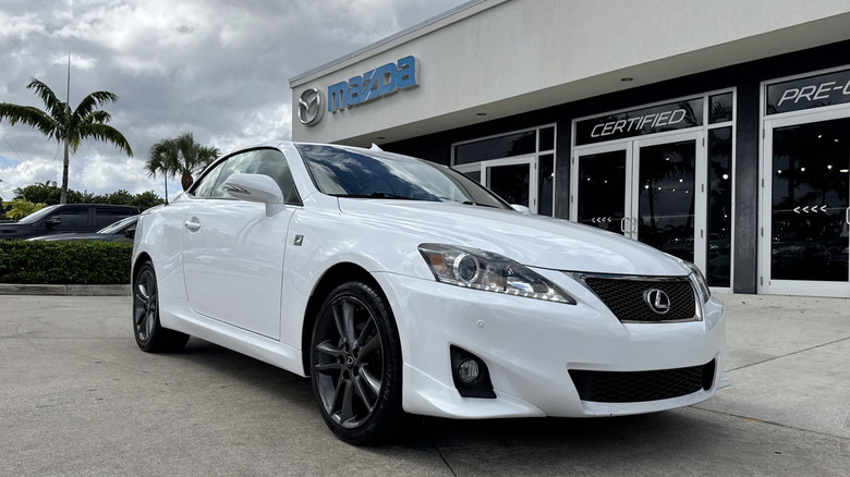 a white Lexus IS250C parked outside of a used car dealership