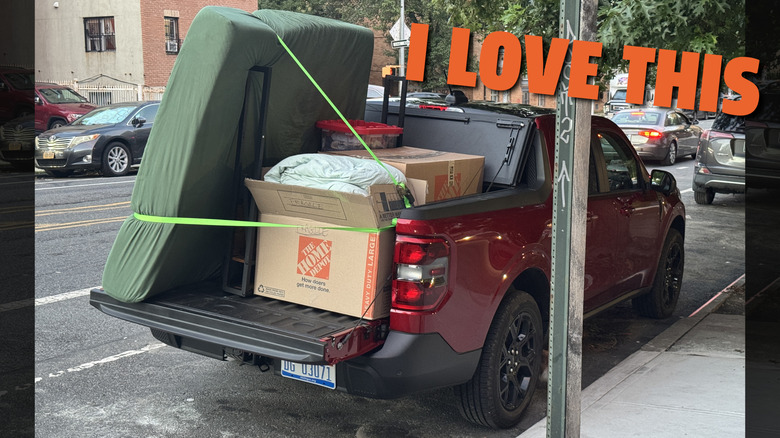 A red Ford Maverick with its bed filled with boxes, bed pieces, and a mattress