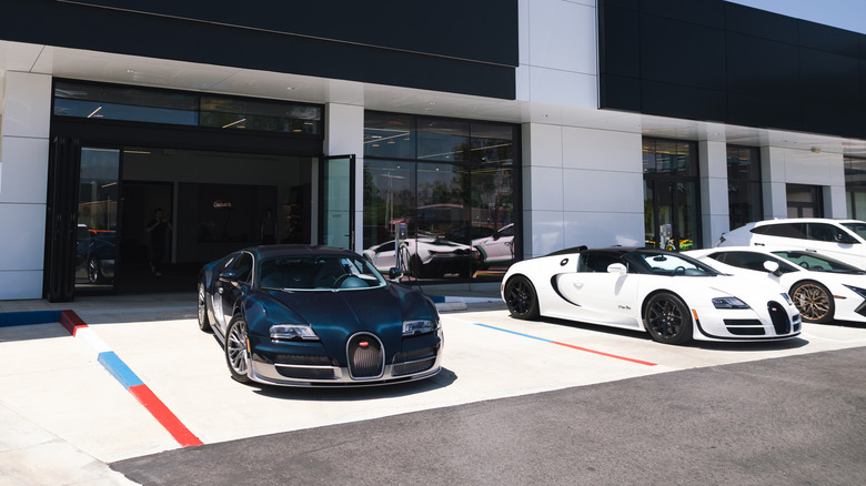 Two Bugatti Veyrons parked in the sun at a dealership