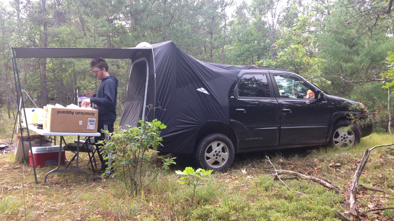The black 2002 Pontiac Aztek in the woods with tent accessory in use.