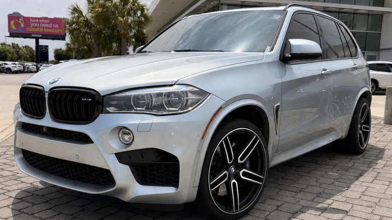 A silver BMW x5M parked in a used car lot