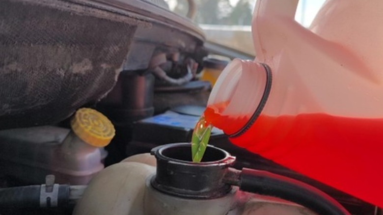 Orange coolant being poured into the car's reservoir
