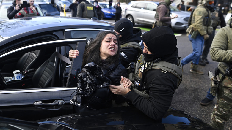 CE agents pull a woman from a car before detaining her on January 13, 2026 in Minneapolis, Minnesota