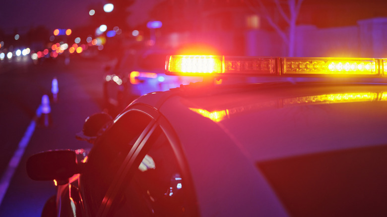 A red light bar on top of a police car performing a traffic stop