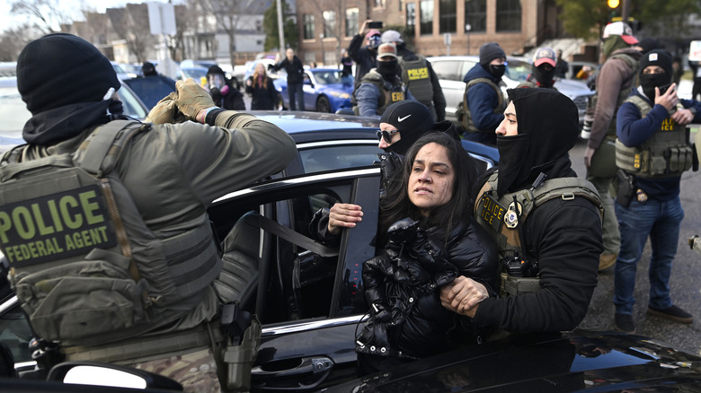 ICE agents pull a woman from a car before detaining her on January 13, 2026 in Minneapolis, Minnesota.