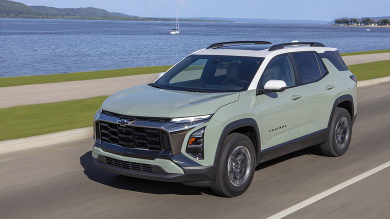 A green and white 2026 Chevrolet Equinox driving on a road.