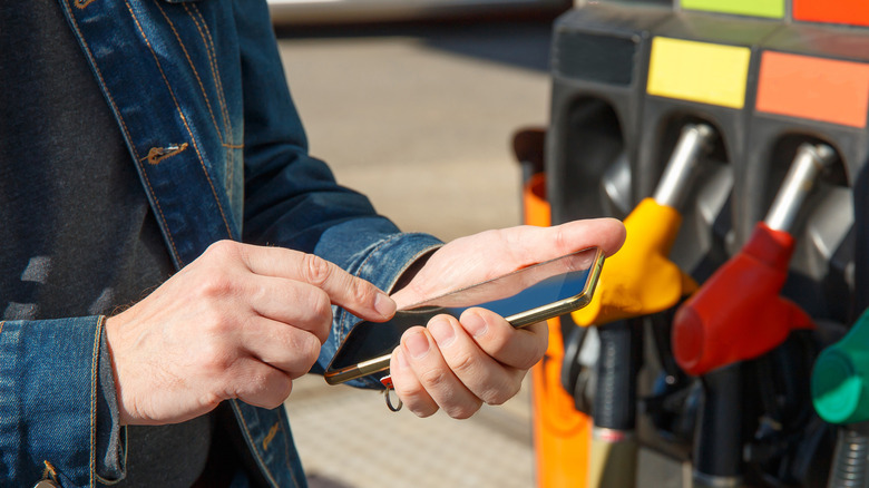 A person using a smartphone app at the gas pump.