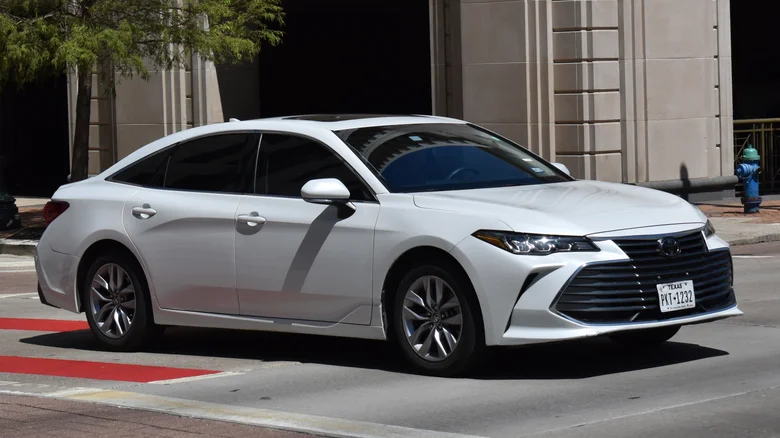 A white Toyota Avalon in front of a building.