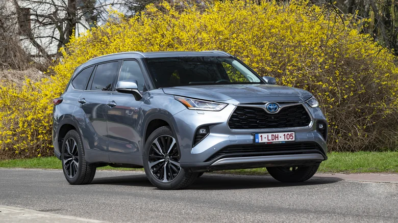 A Toyota Highlander parked in front of a yellow bush.