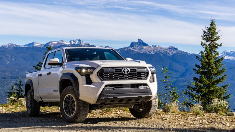 A white Toyota Tacoma on a trail in the mountains.