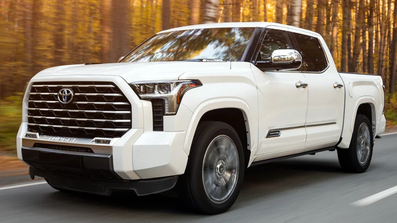 A white Toyota Tundra driving by trees.