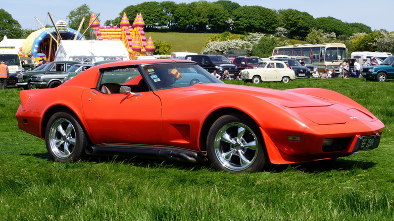 A red 1977 Chevrolet Corvette parked on grass at a show