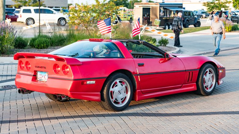 A rear three-quarter view of a red 1980s Corvette convertible