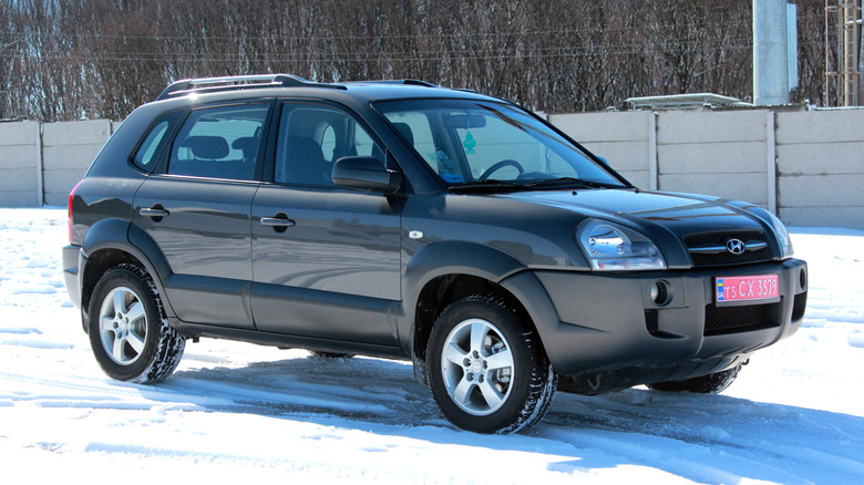 A black first-generation Hyundai Tucson parked on snow in from of a fence.